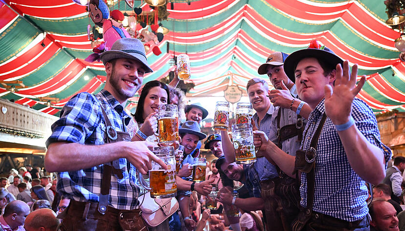 Besucher der Eröffnung des Volksfests Cannstatter Wasen halten Bierkrüge in einem Festzelt in der Hand. Besucher der Eröffnung des Volksfests Cannstatter Wasen halten Bierkrüge in einem Festzelt in der Hand.