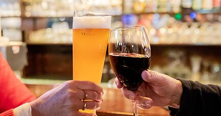 Zwei Gäste stoßen in einer Berliner Gaststätte mit Wein und Bier an.