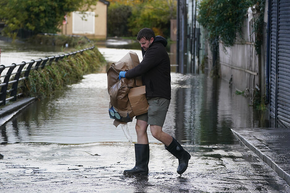 Michael Nugent, der Besitzer von Nugelato Ice Cream in Sugar Island/Großbritannien, trägt Gegenstände über das Hochwasser, nachdem der Kanal der Stadt bei heftigen Regenfällen über die Ufer getreten war.