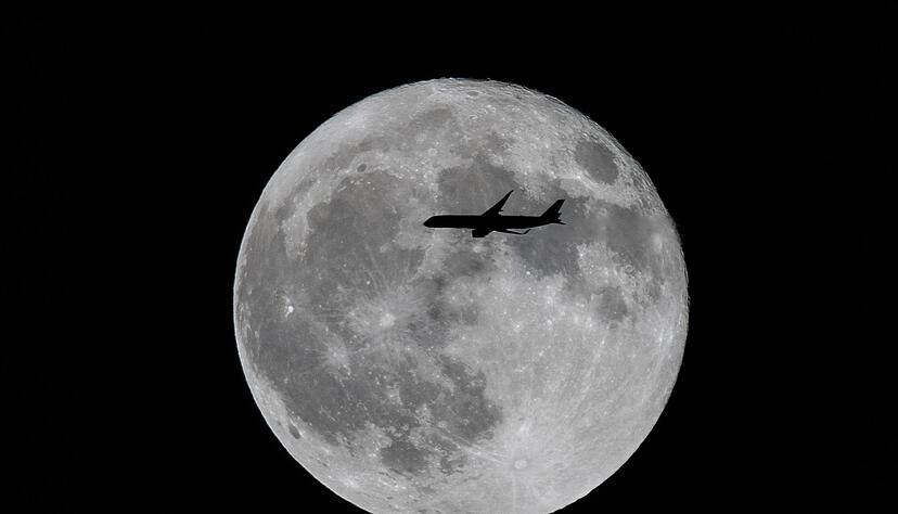 Ein Flugzeug fliegt an einem großen Vollmond vorbei. Ein Flugzeug fliegt an einem großen Vollmond vorbei.