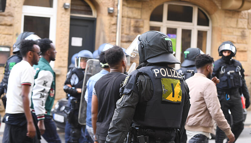 Eine Gruppe von Menschen wird nach Ausschreitungen bei einer Eritrea-Veranstaltung von Polizeikräften eskortiert.