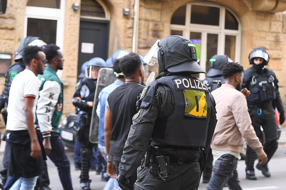 Eine Gruppe von Menschen wird nach Ausschreitungen bei einer Eritrea-Veranstaltung von Polizeikräften eskortiert.