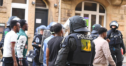 Eine Gruppe von Menschen wird nach Ausschreitungen bei einer Eritrea-Veranstaltung von Polizeikräften eskortiert.
