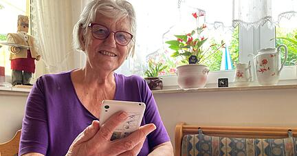 Lydia Ott sitzt mit ihrem Handy am Wohnzimmertisch. Der Betrugsversuch über Whatsapp habe sie gedanklich stark beschäftigt, sagt sie.