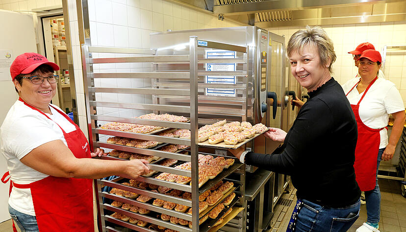 Andrea Fühl (links) und Jennifer Sommer bringen die Pizzabrötchen zum Ofen, wo sie garen. Jeweils fünf Eltern sind in zwei Schichten von morgens bis nachmittags im Einsatz.