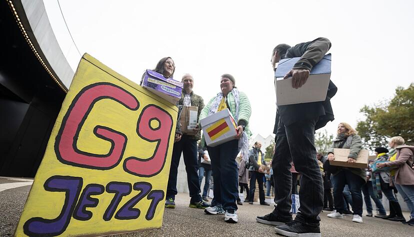 Unterst&uuml;tzer der Elternintiative &bdquo;G9 Jetzt! BW&ldquo; stehen mit Kartons, in denen sich Unterschriftenlisten befinden, vor dem Eingang des B&uuml;rger- und Medienzentrum des Landtags von Baden-W&uuml;rttemberg.