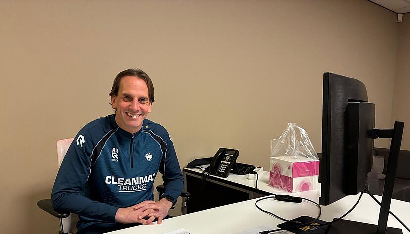 Rüdiger Rehm an seinem Schreibtisch. Der Laptop fehlt, weil er gerade zur Reparatur ist. Rechts auf dem Tisch steht der mitgebrachte Kuchen für die Geschäftsführung.