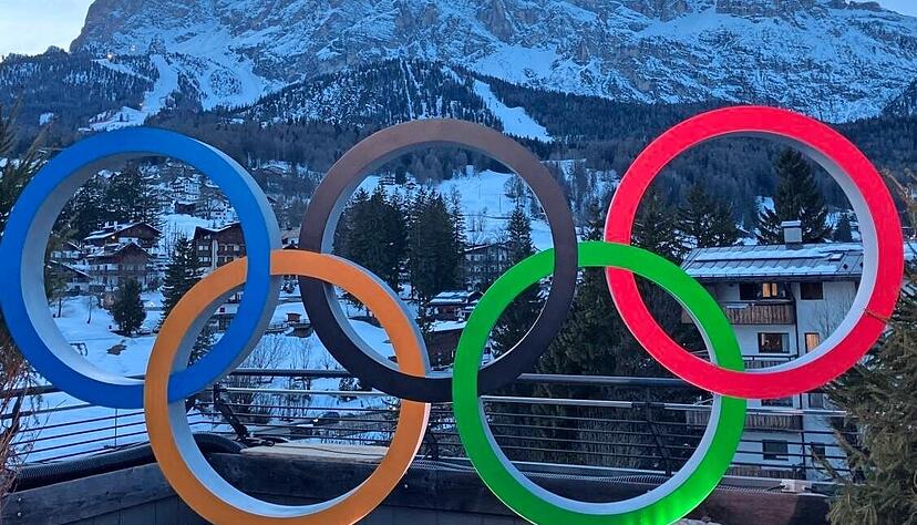 So stellt man sich Olympische Winterspiele vor: Die Ringe am Casa Italia vor verschneiten Bergen, dem Tofana-Massiv.