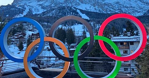 So stellt man sich Olympische Winterspiele vor: Die Ringe am Casa Italia vor verschneiten Bergen, dem Tofana-Massiv.