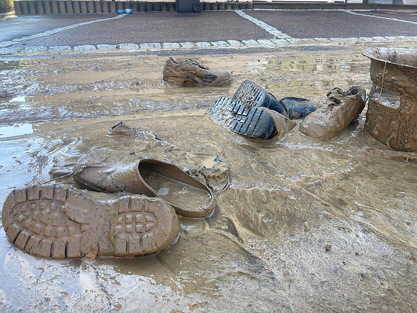 Schuhe liegen verdreckt im Schlamm.