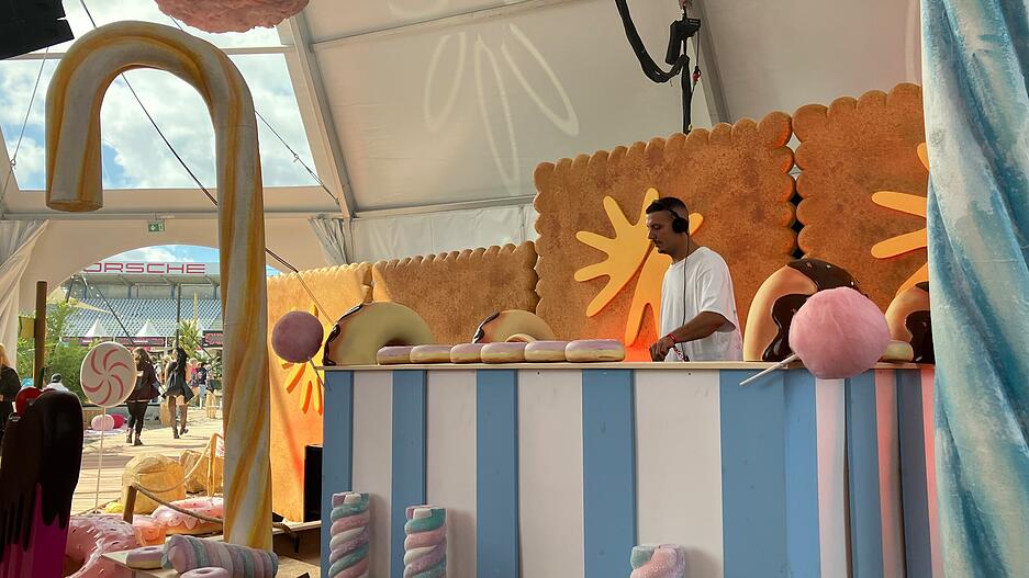 Zwischen bunter Süßigkeiten-Deko legt ein DJ beim Glücksgefühle-Festival auf.