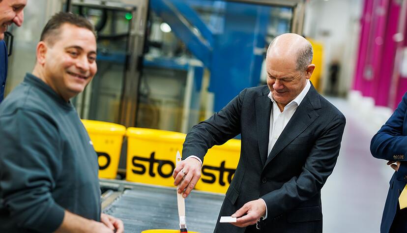 Kanzler Scholz macht beim Baustoffhersteller Sto eine Farbenprobe.