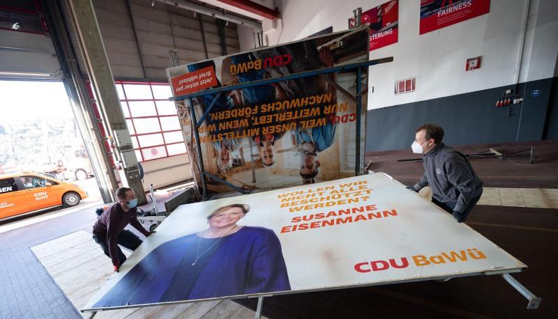 Arbeiter bringen bei ein Wahlplakat der baden-württembergischen CDU zu einem Anhänger.