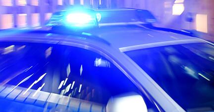 Ein Streifenwagen der Polizei steht mit eingeschaltetem Blaulicht auf der Straße.