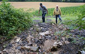 Harald Lepple und Klaus-Dieter Rauch begutachten das Ausmaß. Bis ins Maisfeld hinten zog die Mure Spuren.
Fotos: Friese