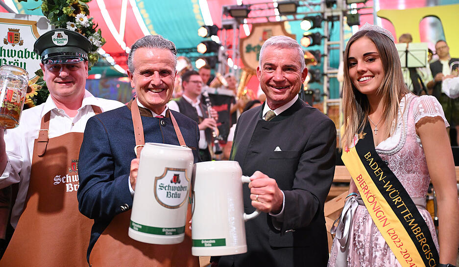 Frank Nopper (2.v.l , CDU), Oberbürgermeister von Stuttgart, hält Cannstatter Wasen zur Eröffnung zusammen mit Thomas Strobl (2. v.r, CDU), Innenminister von Baden-Württemberg, das erste Bier in der Hand. Rechts die Baden-Württemberhische Bierkönigin Amy.