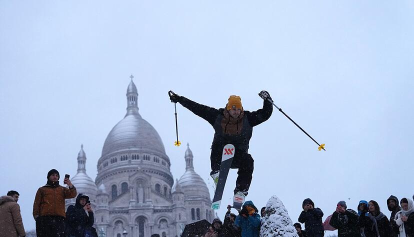 Ein Mann springt mit seinen Skiern den H&uuml;gel bei der Basilika Sacre-Coeur im franz&ouml;sischen Paris hinunter.