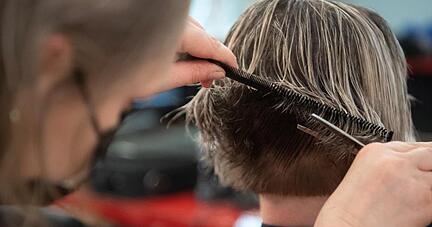 Eine Friseurin schneidet einer Kundin die Haare in einem Friseursalon.