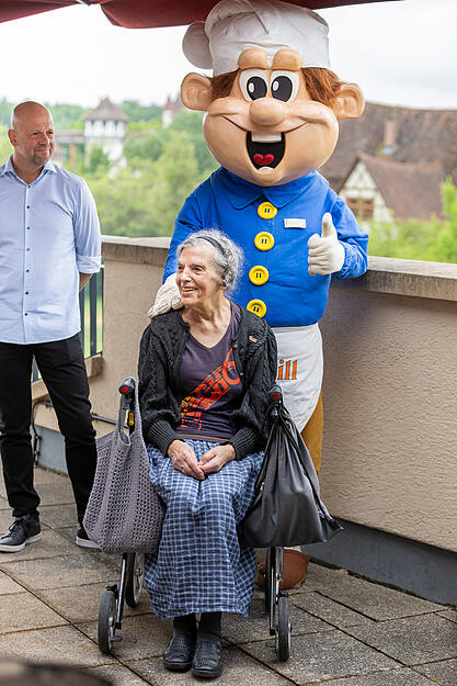 Roland Fischer, von der Tripsdrill-Betreiberfamilie,  feiert die "Schnapszahlfahrt" am Montag mit.  Neben einem Blumenstrau&szlig; &uuml;berreicht er Ursula Dees auch eine Eintrittskarte auf Lebenszeit.