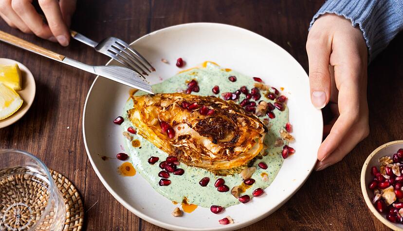 Die Spitzkohl-Viertel werden vor dem Backen kurz in der Pfanne angebraten. Nach 40 Minuten im Ofen werden sie auf Kräuterjoghurt gebettet und mit Granatapfelkernen und Walnüssen getoppt. Die Spitzkohl-Viertel werden vor dem Backen kurz in der Pfanne angebraten. Nach 40 Minuten im Ofen werden sie auf Kräuterjoghurt gebettet und mit Granatapfelkernen und Walnüssen getoppt.