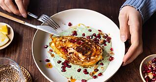 Die Spitzkohl-Viertel werden vor dem Backen kurz in der Pfanne angebraten. Nach 40 Minuten im Ofen werden sie auf Kr&auml;uterjoghurt gebettet und mit Granatapfelkernen und Waln&uuml;ssen getoppt.