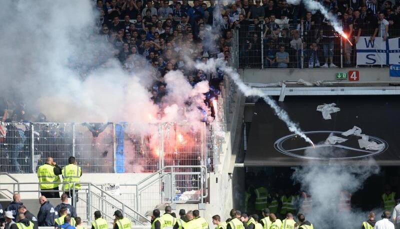 Aus dem Gästeblock beim VfB Stuttgart werden Feuerwerkskörper von KSC-Fans auf das Spielfeld geworfen. Foto: Deniz Calagan