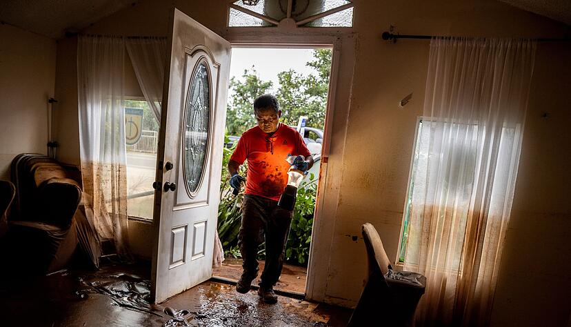 Glenn Duquez, stellvertretender Pastor der Church of God Jesus is Alive Fellowship, tr&auml;gt eine Lampe in das schlammdurchtr&auml;nkte Kirchengeb&auml;ude, um nach der Flut aufzur&auml;umen.