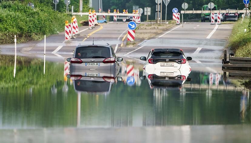 Zwei Autos stehen unter einer Saarbrücke in Saarbrücken im Hochwasser.