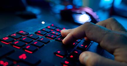 Ein Mann sitzt am Rechner und tippt auf einer Tastatur.