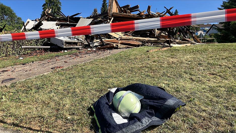 Feuerwehrhelm und -jacke liegen am Sonntag vor der niedergebrannten Kirche in Widdern.