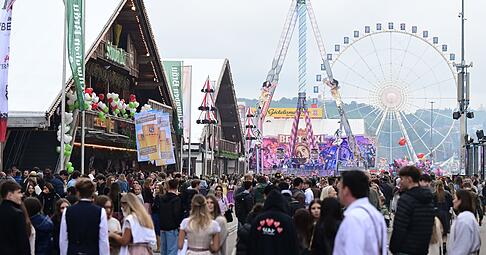 Besucher des Cannstatter Volksfestes stehen vor einem Bierzelt.
