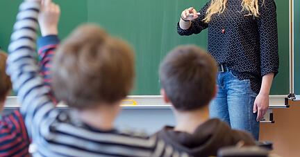 Eine Absolventin eines Freiwilligen Sozialen Jahres (FSJ) hilft beim Unterricht in einer 3. Klasse in der Grundschule.
