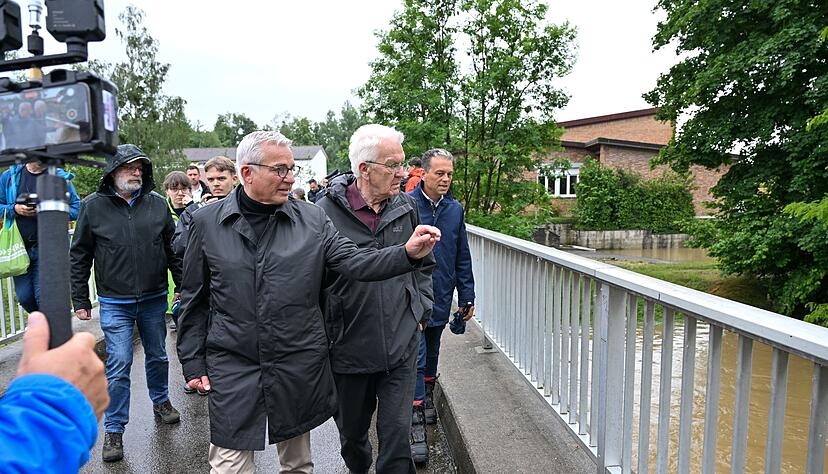 Winfried Kretschmann (Grüne, 2.v.r), Ministerpräsident von Baden-Württemberg, und Landesinnenminister Thomas Strobl (CDU, 3.v.r) schauen die Hochwasserlage in Kehlen an, Im Hintergrund ist die Grundschule von Kehlen zu sehen.