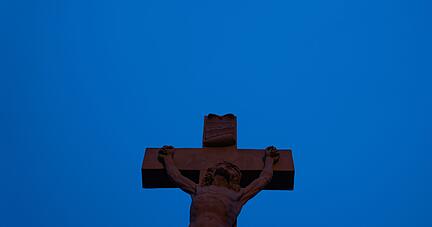 Eine Jesusskulptur zeichnet sich vor dem Firmament ab - blaue Stunde in Bamberg.