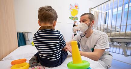Ein Arzt untersucht in einer Kinderklinik ein Kind.