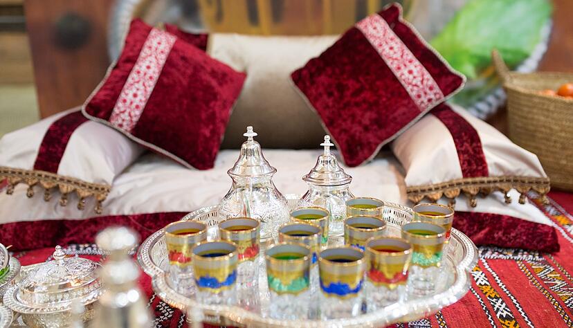 Bodenkissen und bunte Teegl&auml;ser: Eine Sitzecke mit marokkanischem Flair im Wohnzimmer kann Urlaubsgef&uuml;hle wecken oder an eine fr&uuml;here Reise erinnern.