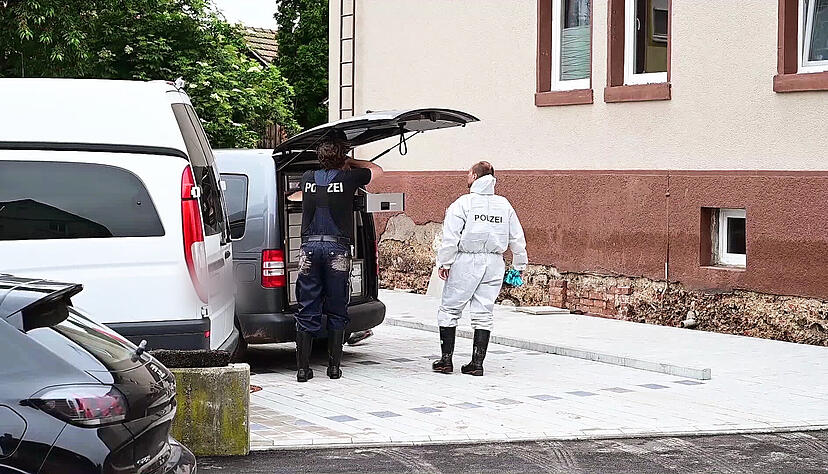 Polizeibeamte der Spurensicherung stehen an ihrem Auto im Stadtteil Miedelsbach. Sie untersuchen einen Fundort von zwei Leichen, die nach einem Unwetter in einem Keller gefunden worden waren.