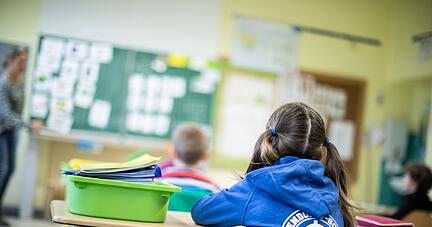 Schülerinnen und Schüler einer Grundschule sitzen in ihrem Klassenraum.