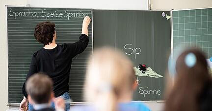 Eine Lehrerin schreibt in einer Schule an die Tafel.