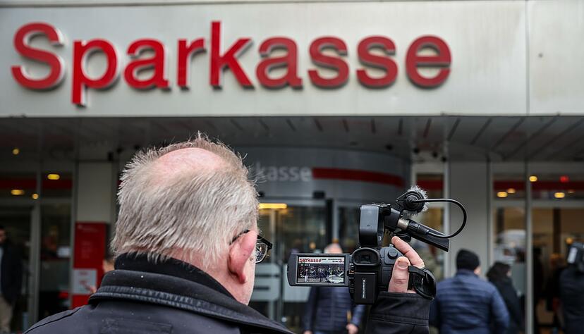 Ein Medienvertreter steht mit einer Kamera vor der Sparkassenfiliale in Buer.