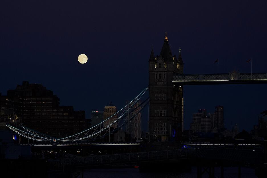 Hinter der Tower Bridge in London zeigt sich der Supermond am Himmel.