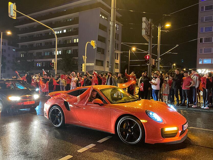 Aus den Autos beim Korso hängen Flaggen.