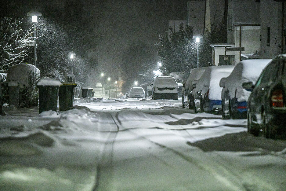 Titisee-Neustadt: Schnee bedeckt Straßen, Mülltonnen und geparkte Fahrzeuge in einer Wohnstraße bei Nacht. Titisee-Neustadt: Schnee bedeckt Straßen, Mülltonnen und geparkte Fahrzeuge in einer Wohnstraße bei Nacht.