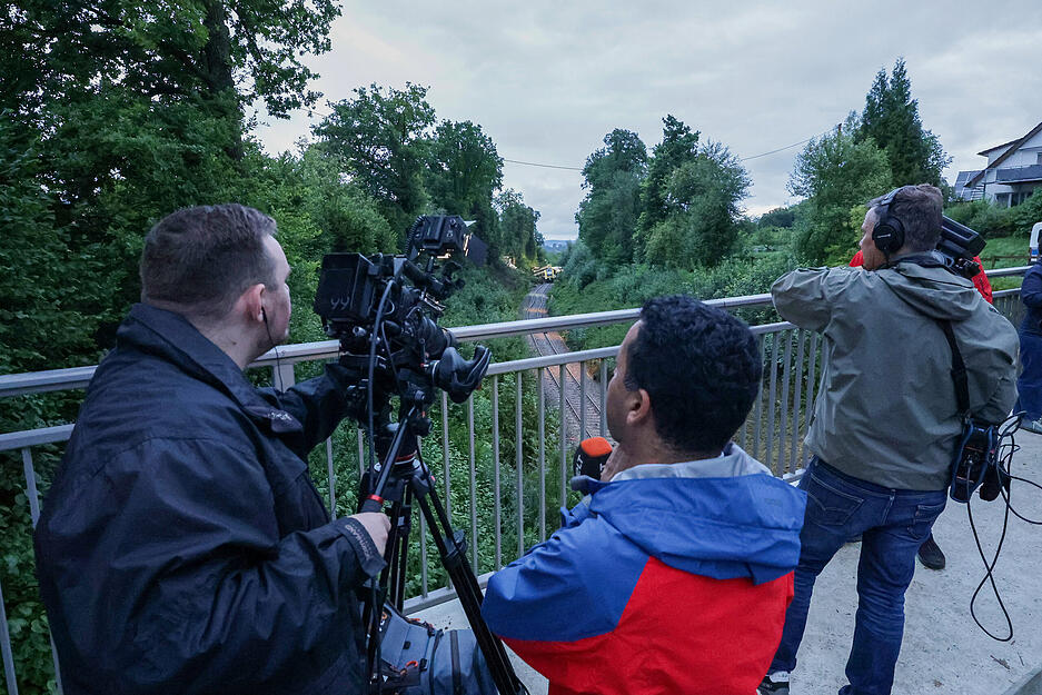 Medienvetreter filmen den entgleisten Personenzug bei Zell von einer Brücke aus.