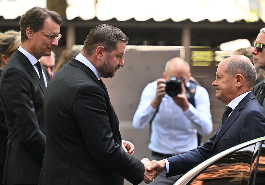 Bundeskanzler Olaf Scholz (SPD, r) wird von Hendrik Wüst (CDU; l), Ministerpräsident von Nordrhein-Westfalen, und von Tim Kurzbach (SPD, M), Oberbürgermeister der Stadt Solingen, bei seiner Ankunft begrüßt.