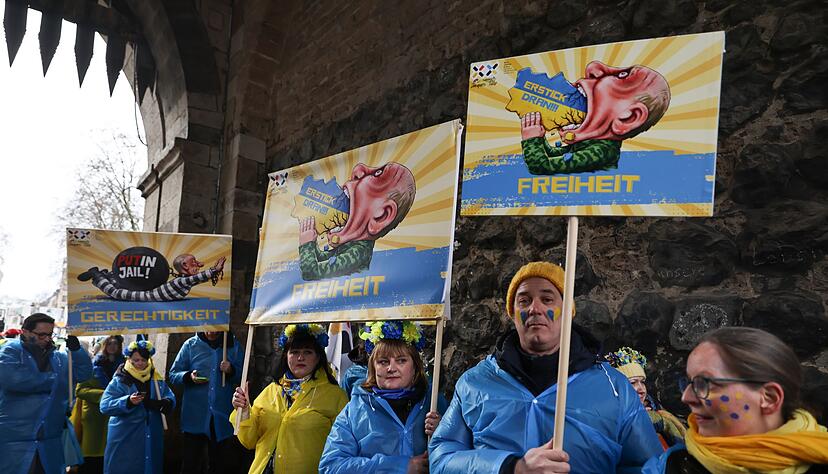 Mitglieder des ukrainischen Hilfsvereins Blau-Gelbes Kreuz halten im Kölner Rosenmontagszug Plakate mit früheren Putin-Darstellungen aus den Zügen in Köln und Düsseldorf hoch. Mitglieder des ukrainischen Hilfsvereins Blau-Gelbes Kreuz halten im Kölner Rosenmontagszug Plakate mit früheren Putin-Darstellungen aus den Zügen in Köln und Düsseldorf hoch.