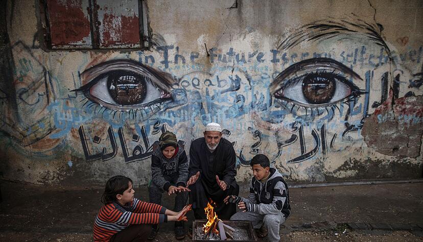 Palästinensische Kinder wärmen sich mit ihrem Großvater an einem Feuer in Gaza-Stadt (Archiv).