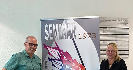 Martina Geiger und Karsten Wiese vor dem Plakat, das am Eingang des Geb&auml;udes zwischen Polizeirevier und Finanzamt-Au&szlig;enstelle auf das 50-j&auml;hrige Bestehen des Heilbronner Lehrerseminars aufmerksam macht.
Foto: Susanne Schwarzb&uuml;rger,