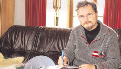 Johannes von Buttlar (71) signiert in seiner Bibliothek ein Buch. Hund Dusel leistet ihm Gesellschaft, muss aber nach einer Operation noch eine Halskrause tragen.