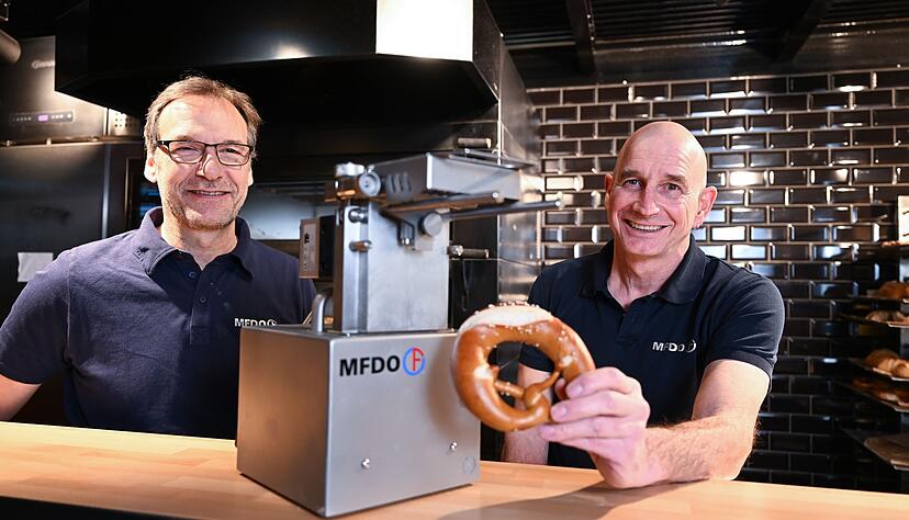 Michael Feil (l) und Dieter Obertautsch (r), die Erfinder und Entwickler einer einer Butterbrezel-Bef&uuml;llungsmaschine, stehen mit ihrer Entwicklung in einem B&auml;ckerei-Laden in der Markthalle.